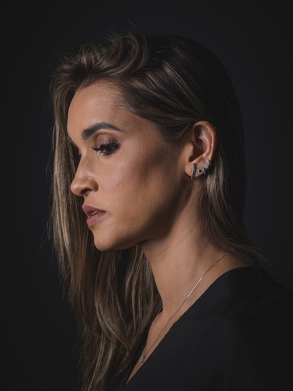 Fernanda Alisk, fundadora da Fê Ponto Joias, em retrato editorial sobre fundo escuro